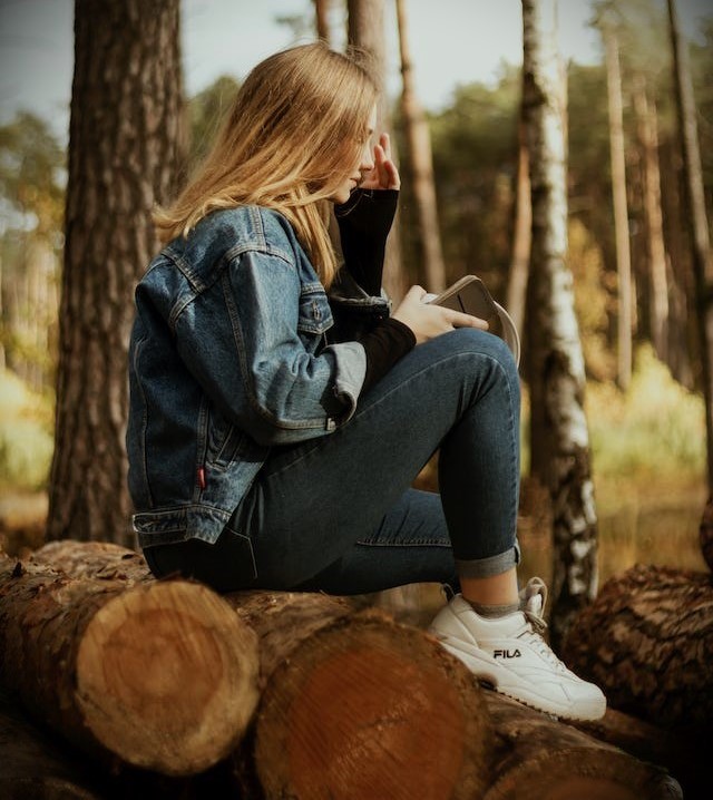 森の中で丸太に座っている女性